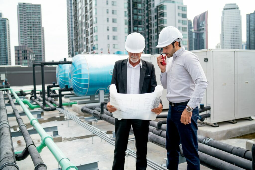 Young engineer man use walkie talkie to contact with his team and stand beside senior coworker